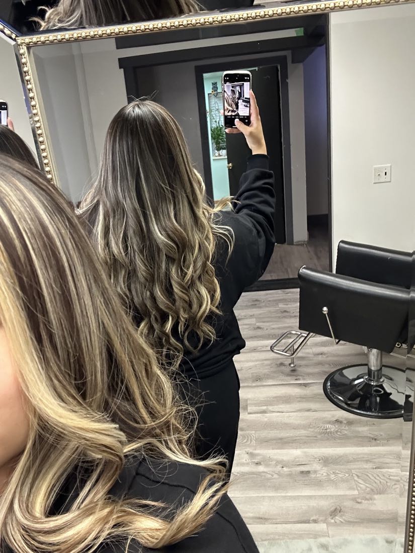 Blonde balayage with soft waves styled at Salon De Belleza Lily, shown in the salon mirror